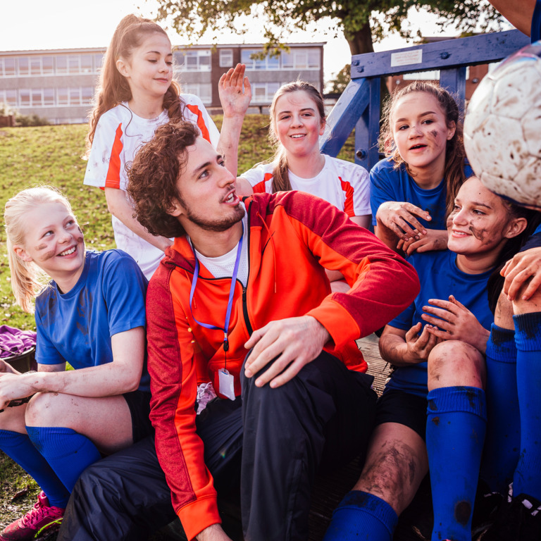 Junger Mann im Ehrenamt mit Kinder-Fußballmannschaft