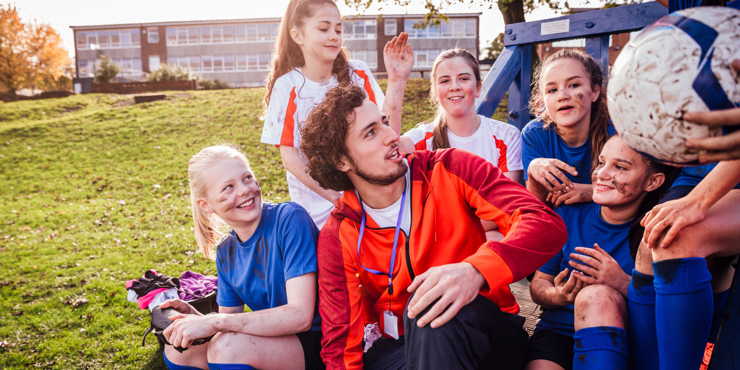 Junger Erwachsener voluntiert und trainiert eine junge Mädchenmannschaft