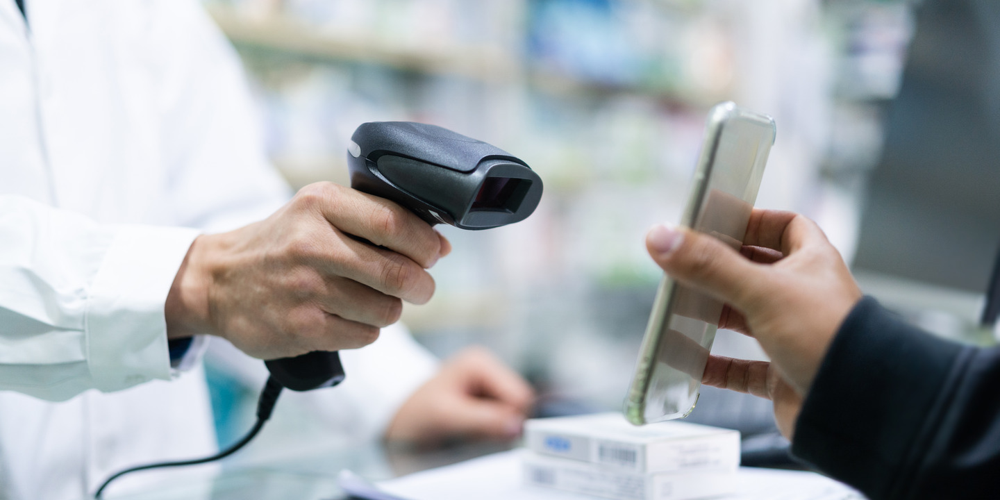 Apotheker richtet Scanner auf Handy eines Kunden