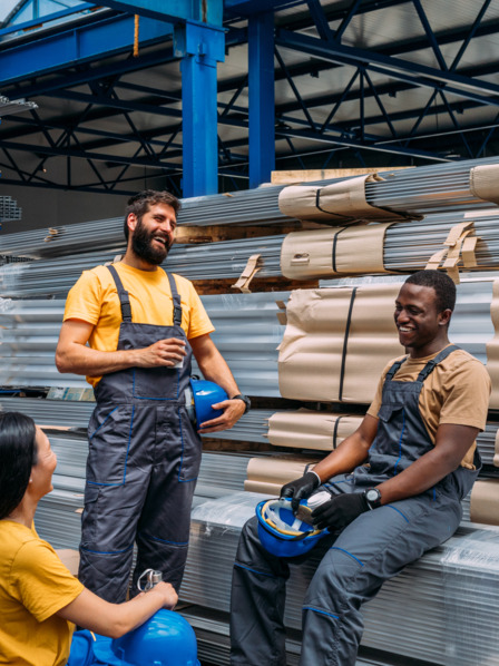 Mehrere Arbeiter stehen in Produktionshalle zusammen und lachen