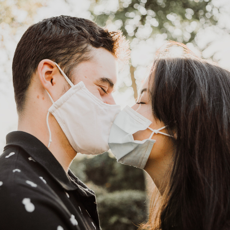 Paar küsst sich mit Maske