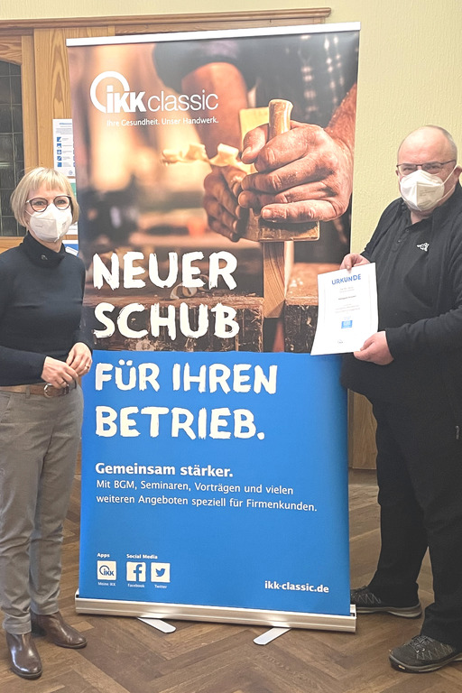 IKK-Gesundheitsmanagerin Sabine Tast (links) übergibt Dieter Krückel (rechts) die Urkunde für „Exzellentes betriebliches Gesundheitsmanagement“