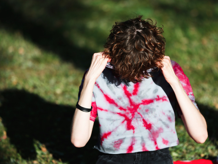 Person mit Burnout vergräbt Gesicht in T-Shirt