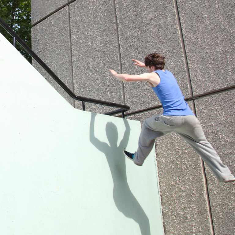 Junger Mann rennt Parcours an Hauswand