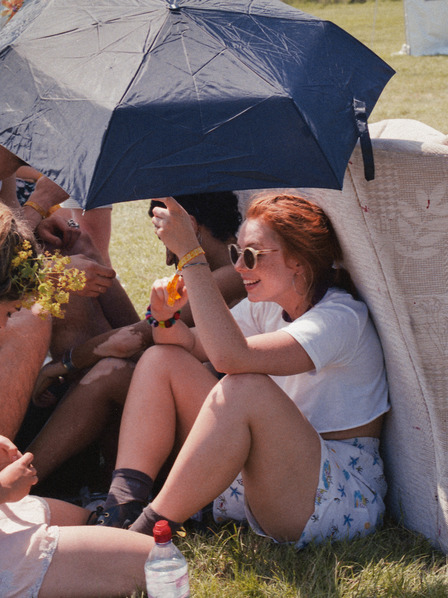 Gruppe junger Leute schützt sich mit Regenschirmen vor der Sonne