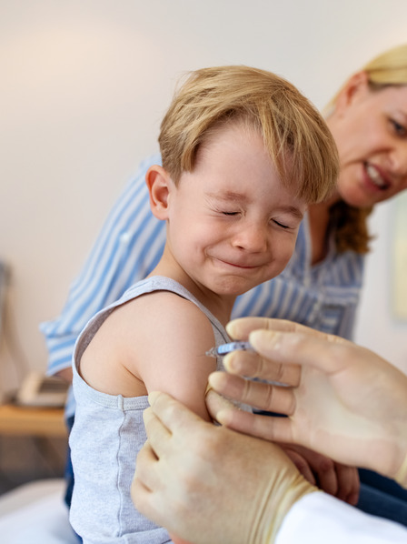 Junge schließt während der Impfung beim Kinderarzt die Augen