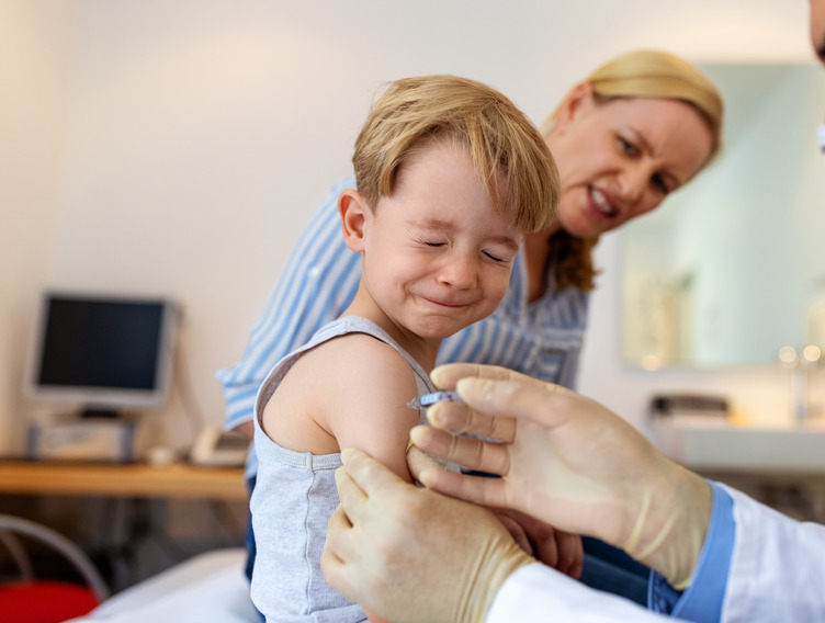 Junge schliesst während der Impfung die Augen beim Hausarzt