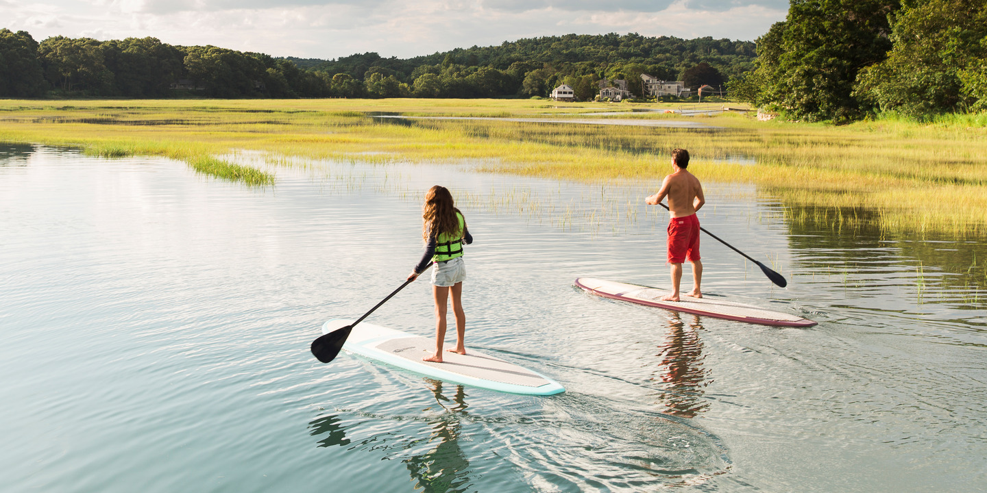 Junge Frau und Mann auf Stand-up-Paddle am See
