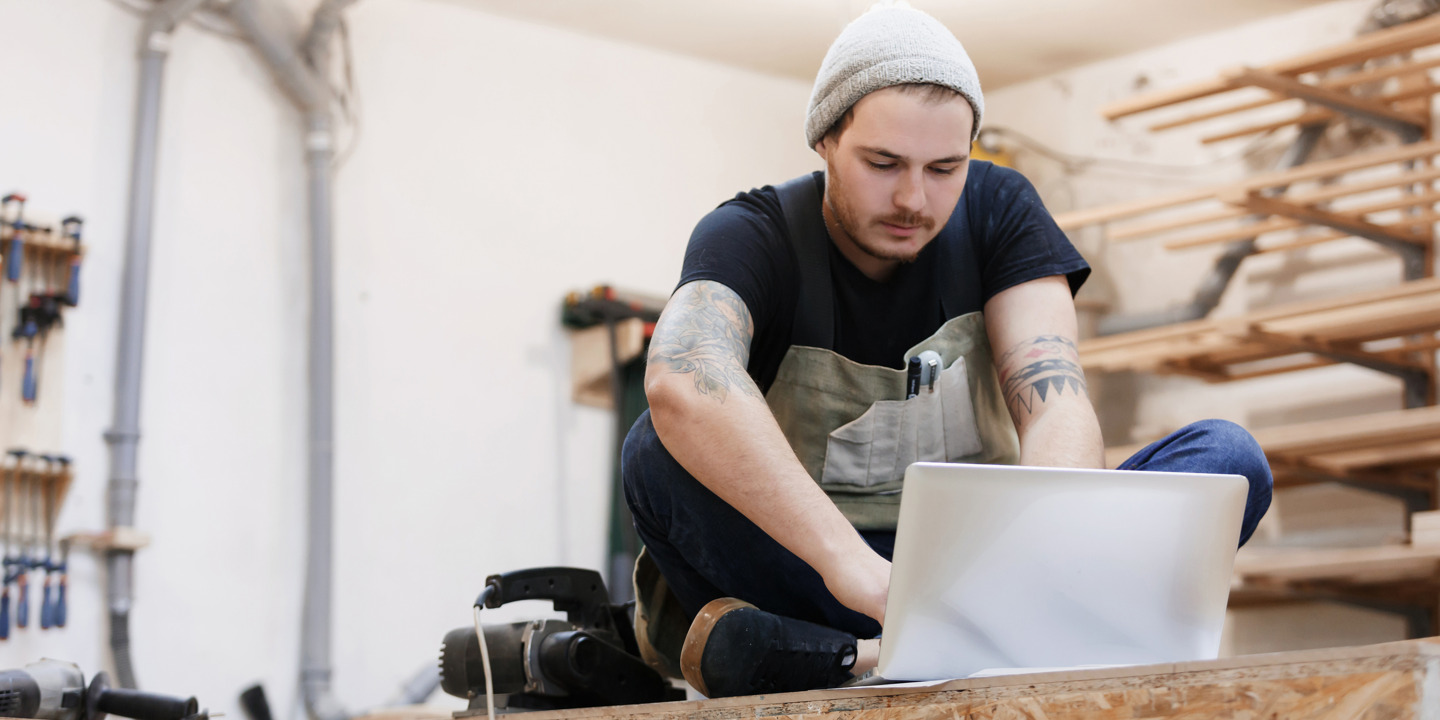 junger Handwerker schreibt sein Berichtsheft am Laptop