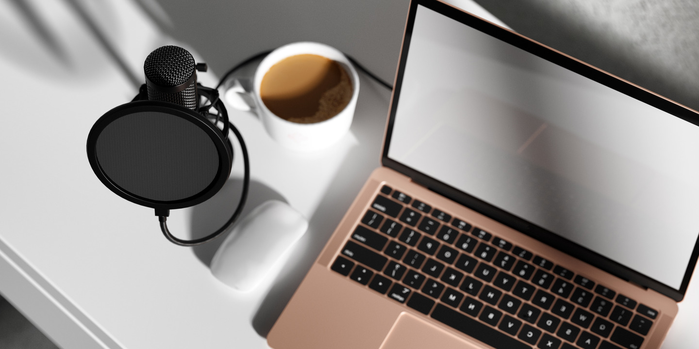 Ein Tisch mit Mikrofon, Laptop und Kaffeetasse