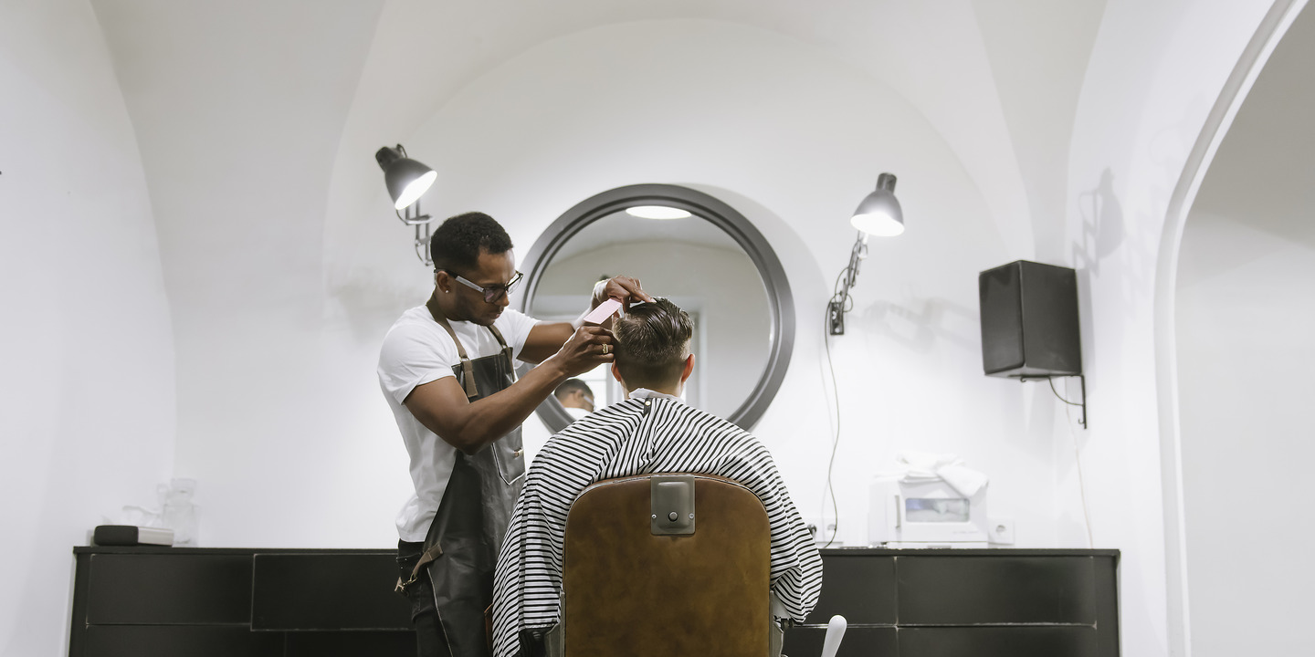 Friseur schneidet einem Kunden die Haare im Friseursalon