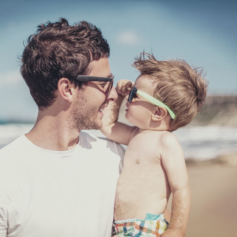 Vater und Sohn betrachten sich durch Ihre Sonnenbrillen am Strand