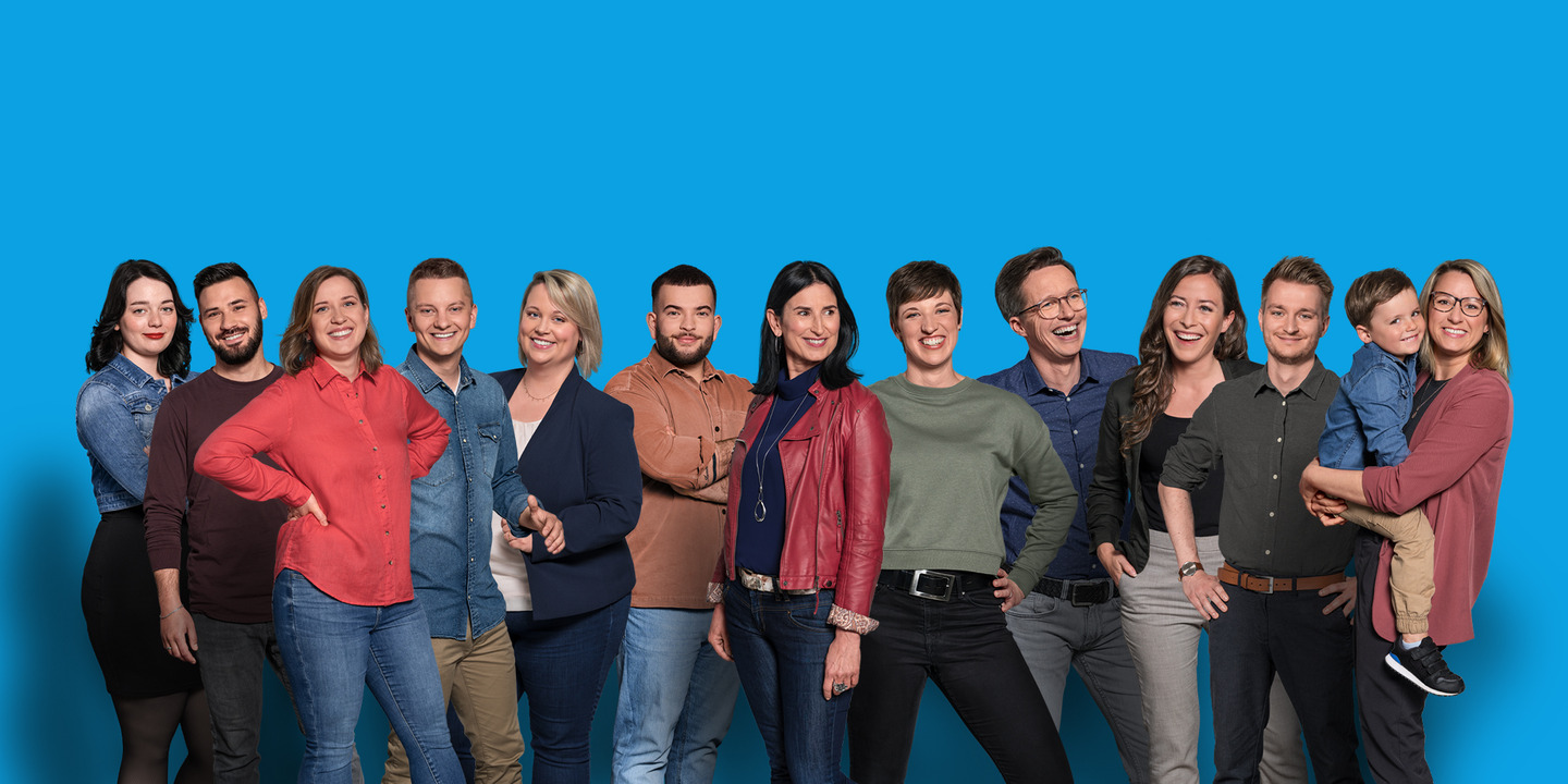 12 Mitarbeiter der IKK classic stehen vor blauem Hintergrund
