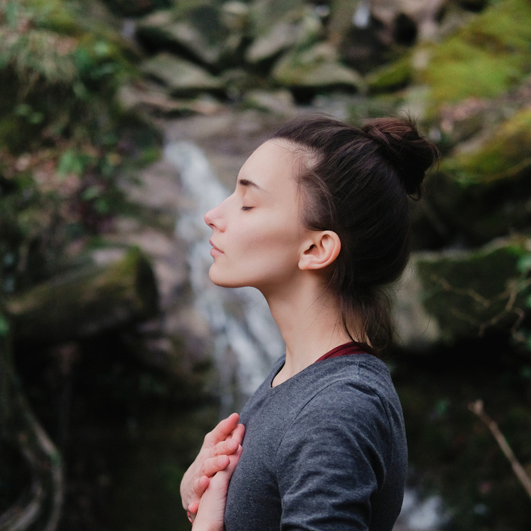 Junge Frau meditiert im Wald
