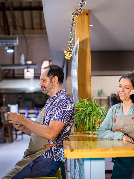 Zwei Kellner:innen stehen im Restaurant und benutzen ihr Smartphone