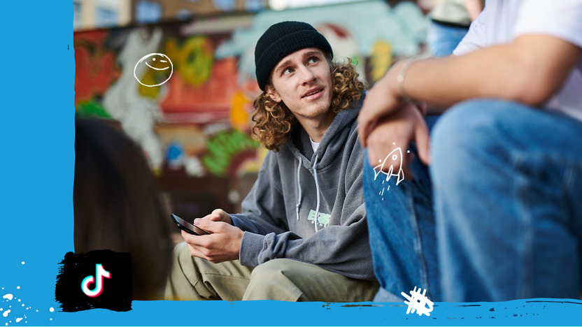 Junger Mann sitzt mit Freunden im Skaterpark
