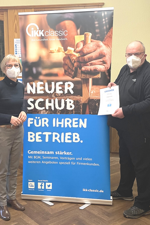IKK-Gesundheitsmanagerin Sabine Tast (links) übergibt Dieter Krückel (rechts) die Urkunde für „Exzellentes betriebliches Gesundheitsmanagement“