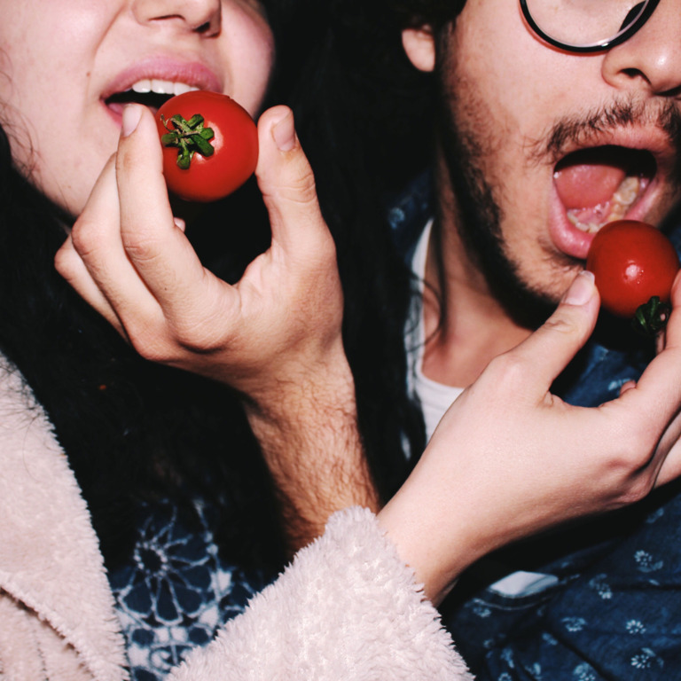 Eine Frau und ein Mann stekcen sich gegenseitig Tomaten in den Mund.