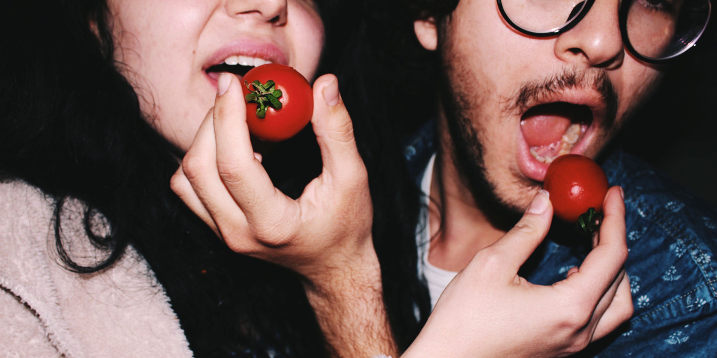 Mann und Frau füttern sich gegenseitig mit Tomate