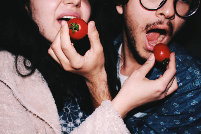 Eine Frau und ein Mann stekcen sich gegenseitig Tomaten in den Mund.