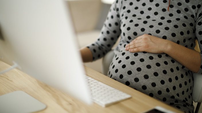Schwangere Frau sitz vor einem Computerbildschirm