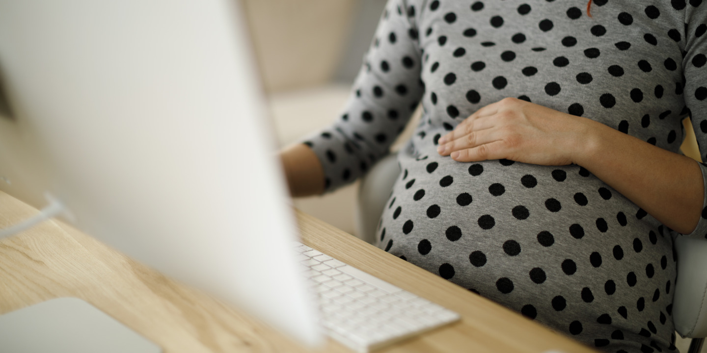 schwangere Arbeitnehmerin arbeitet am Rechner