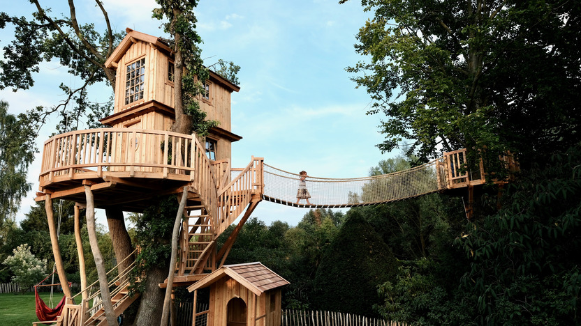 aufwändig gestaltetes Baumhaus aus Holz mit Hängebrücke