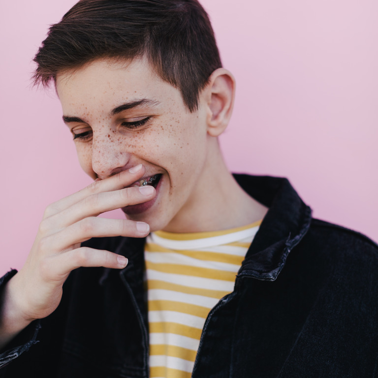 Teenager hält sich lachend eine Hand vor den Mund
