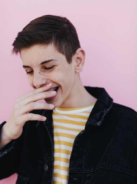Teenager hält sich lachend eine Hand vor den Mund