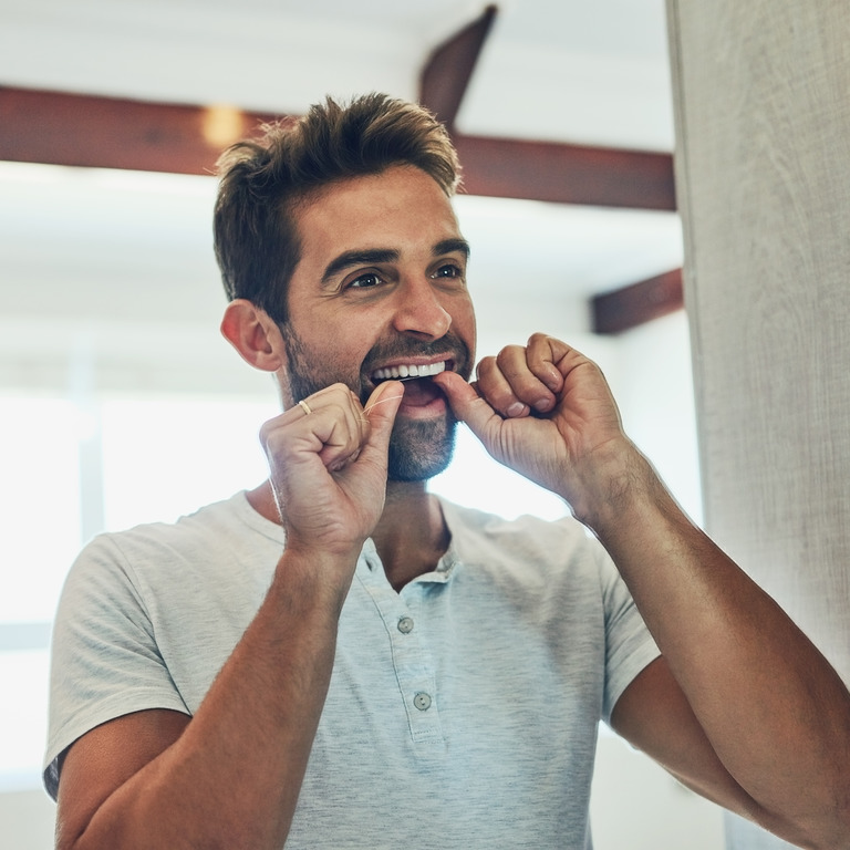 Mann reinigt seine Zähne mit Zahnseide