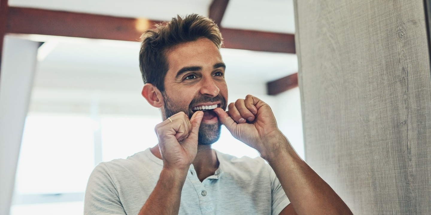 Mann reinigt mit Zahnseide seine Zähne
