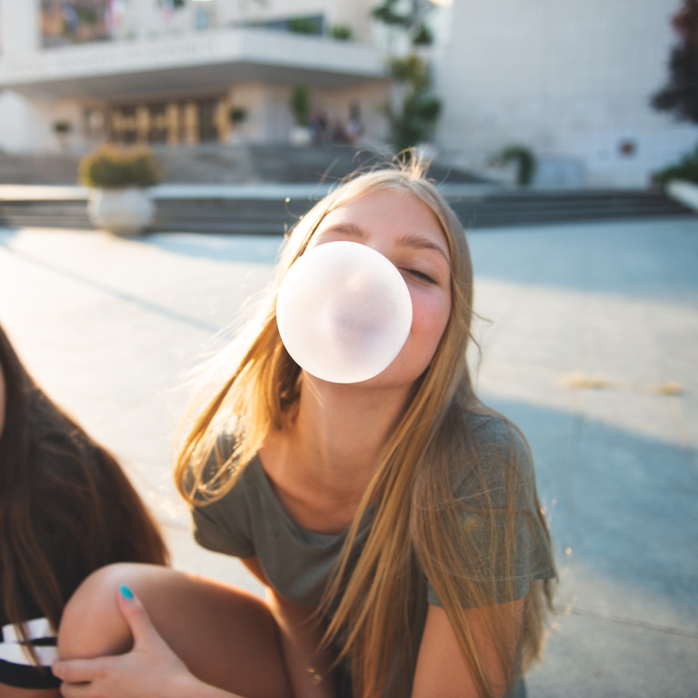 Zwei Mädchen formen Kaugummiblasen mit Mund