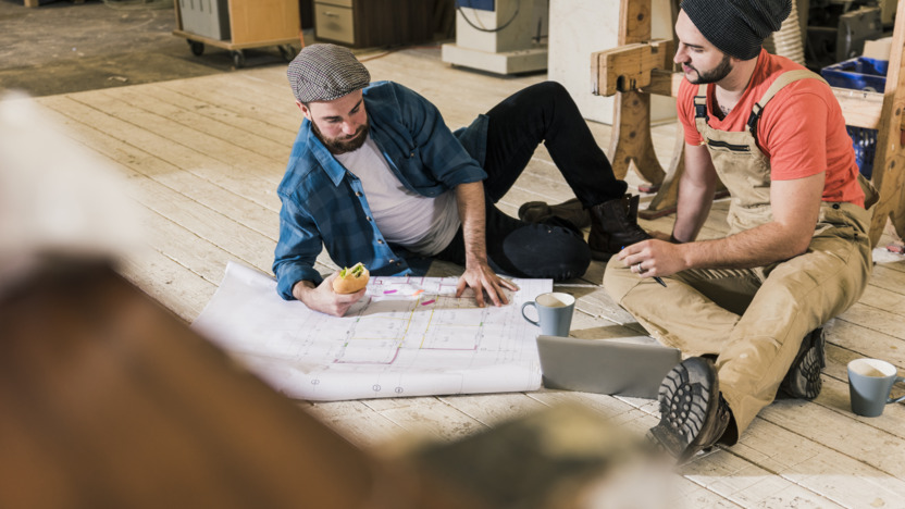 zwei junge Handwerker studieren einen Grundriss