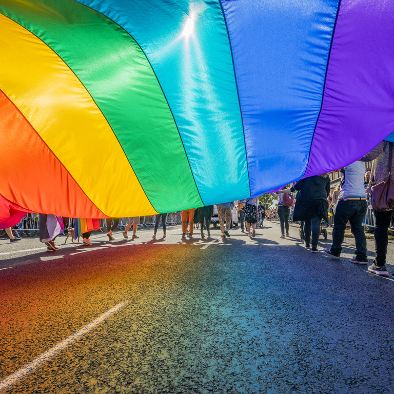Ein Wurftuch in Regenbogenfarben auf einer Straßenparade.