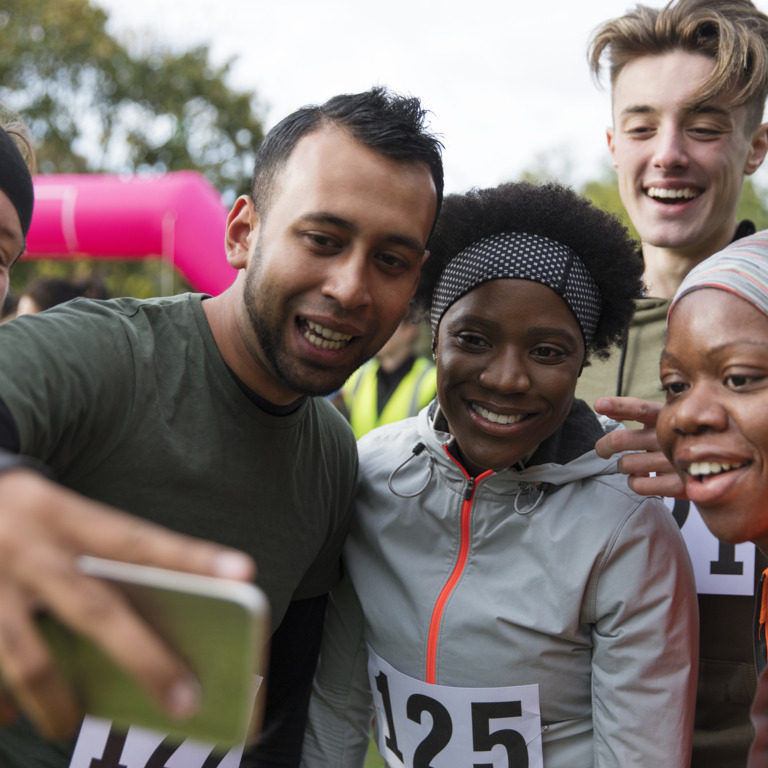 Menschen unterschiedlichster Nationalität in Laufkleidung machen nach einem Laufwettbewerb ein Gruppen-Selfie