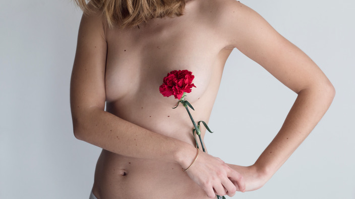 Oberkörper einer Frau, Brust wird durch eine Blume mit roter Blüte verdeckt