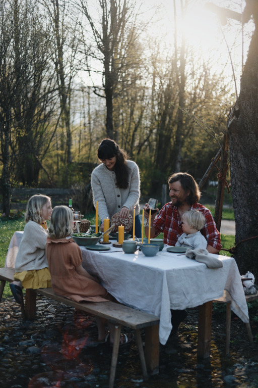 Familie isst im Garten an gedecktem Tisch.