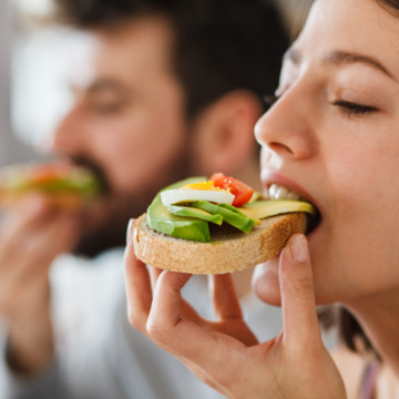 Junge Frau beißt genüsslich in ein mit Avocado belegtes Brot