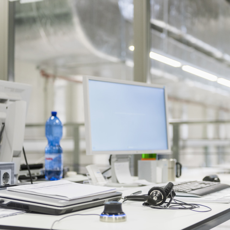 Schreibtisch mit Computer, Headset und Wasserflasche