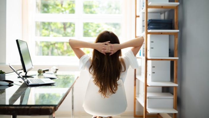 Frau sitzt im Büro auf Stuhl und entspannt sich