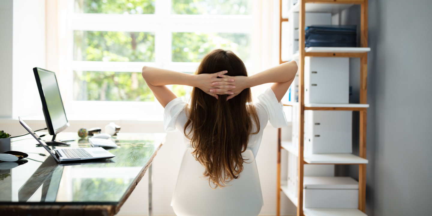 Frau sitzt im Büro auf Stuhl und entspannt sich