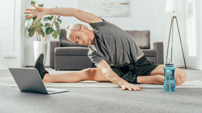 Mann macht einen Online-Sportkurs Zuhause.