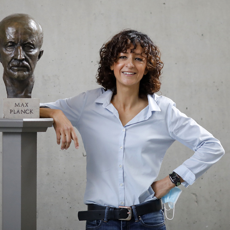 Emmanuelle Charpentier lehnt an Statue von Max Planck