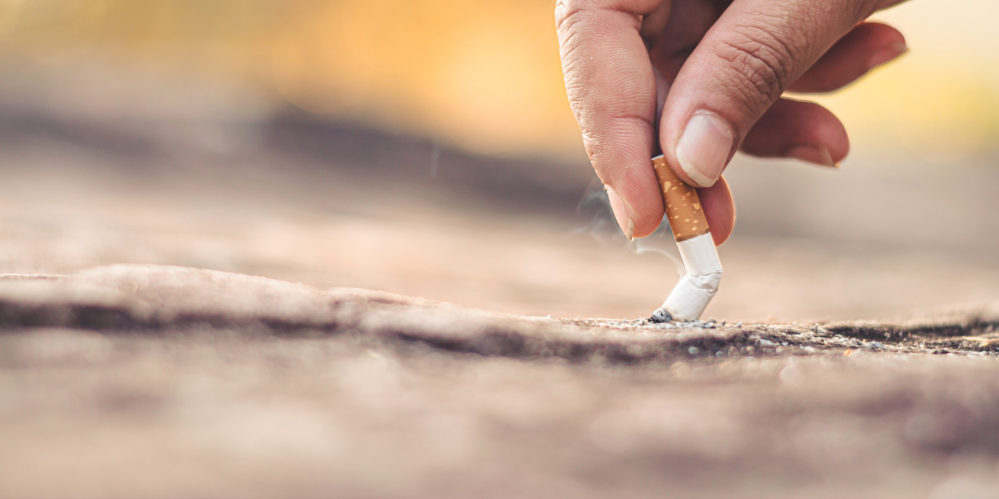 Hand drückt Zigarette auf Boden aus
