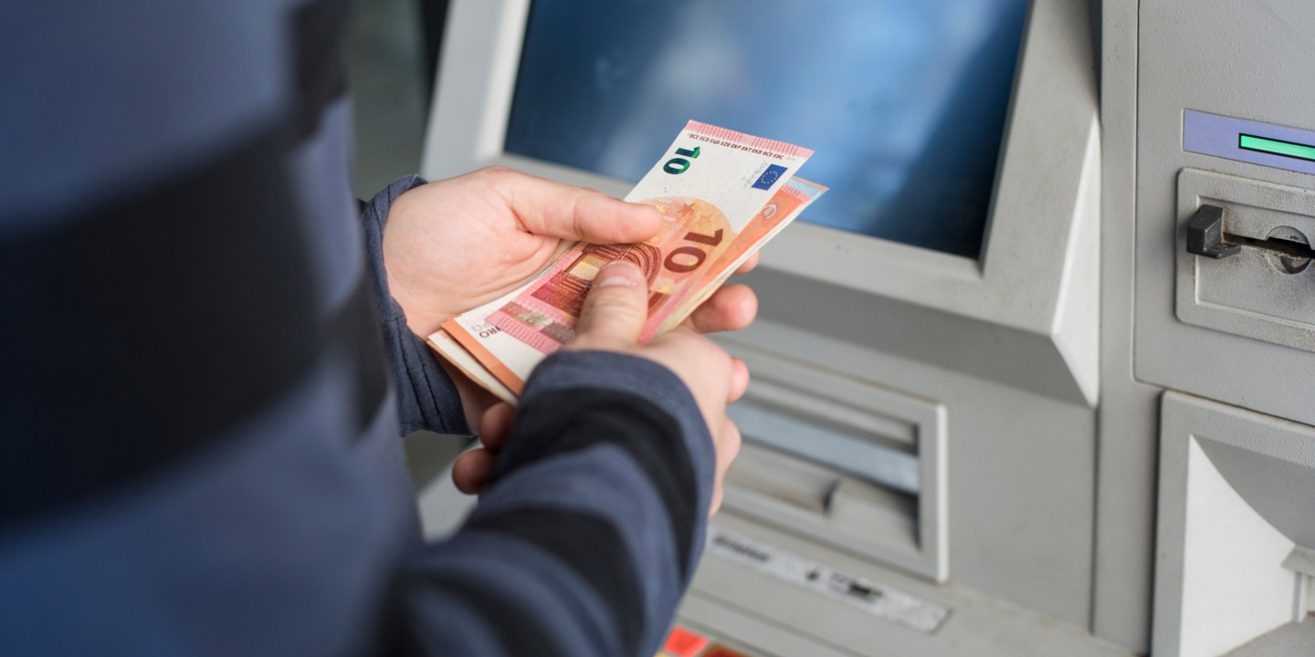 Person hebt Geld vom Automaten ab.