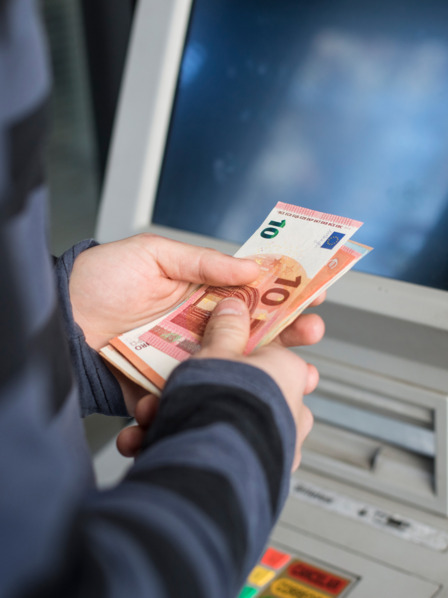Person hebt Geld vom Automaten ab.