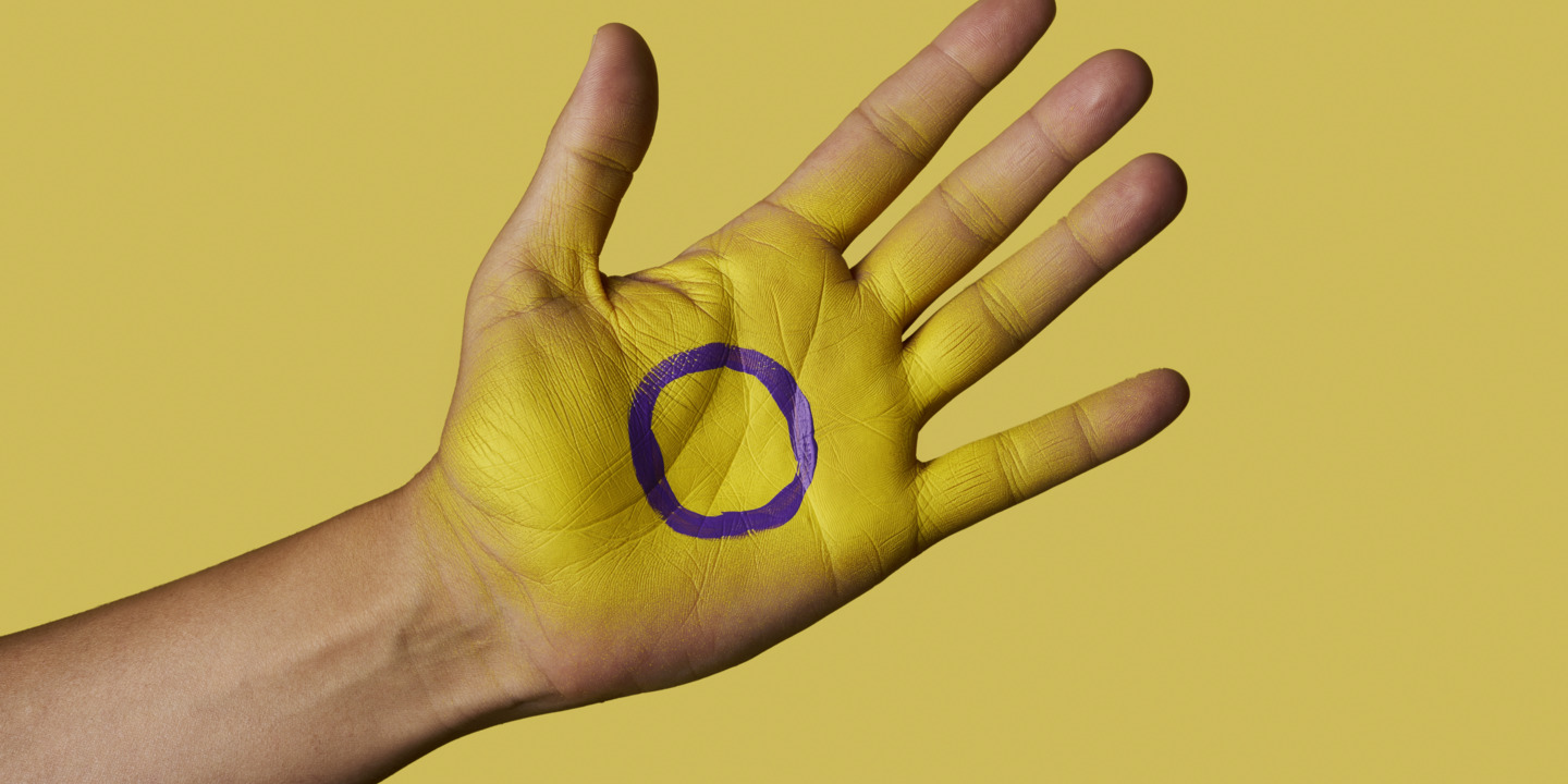 Das Flaggensymbol für Intersexualität gemalt auf eine Handfläche