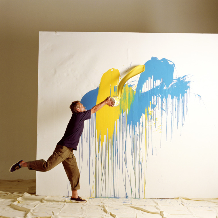 Mann spritzt Farbe an eine große Leinwand