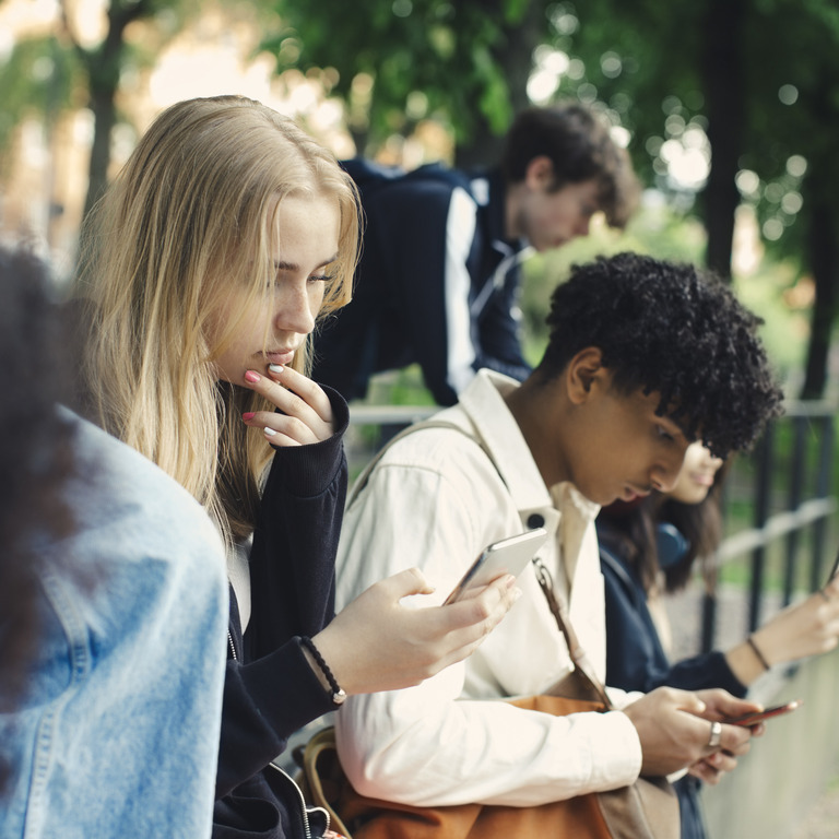 Gruppe Jugendlicher richtet ihren Blick auf ihre Smartphones