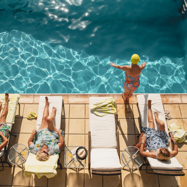 Vier Seniorinnen liegen am Rand eines Swimming Pools